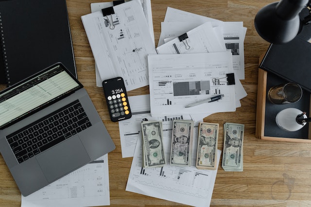 stacks of money on top of documents spread out on a desk